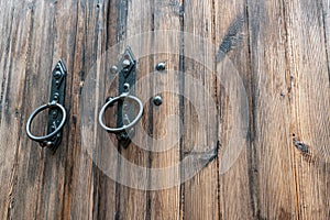 Old wooden doors. Iron rings on the gate. Decoration elements of buildings, vintage iron door handles, knockers and gong handle