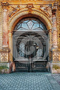 Old wooden doorway with broken glass and worn wrought iron decoration