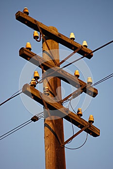Old wooden electric pole in blue clear sky at sunset