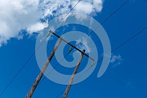 Old wooden electric post against blue sky and clouds