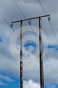Old wooden electric post against blue sky and clouds