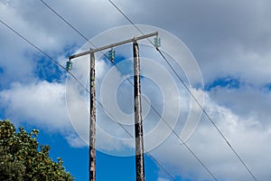 Old wooden electric post against blue sky and clouds