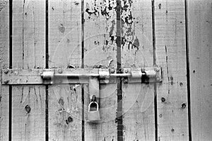 Old wooden entrance gate with padlock and cracked paint