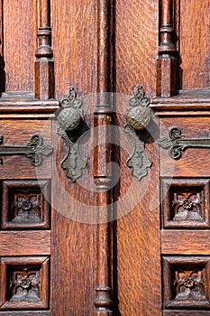 Old wooden exterior doors with decorative panels, brass doorknobs photo