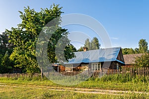 Old, wooden farm house, situated in the countryside, between the trees in the summertime.