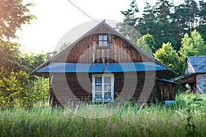 Old, wooden farm house, situated in the countryside, between the trees in the summertime.