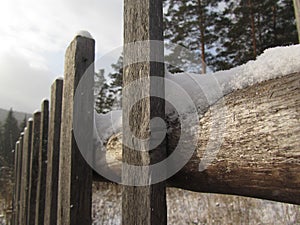 Old wooden fence in the snow. Close-up. Copy space. Winter village scene.