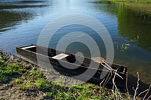 An old wooden fishing boat near the shore of the river. Beautiful nature