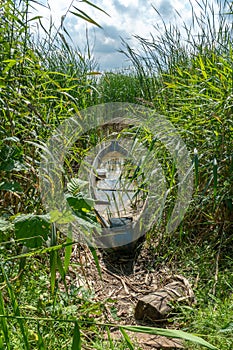 An old wooden fishing boat is submerged near the shore of the lake. The boat was moored in the thicket after the shipwreck. A