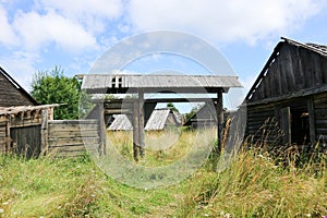 Old wooden gates in abandoned village overgrown by grass