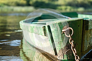 An old wooden, green boat on the river. Fishing rod with a float in the river. Fishing