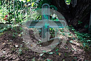 Old wooden green cross on the grave