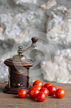 Old wooden grinder for pepper and cherry tomatoes on wooden table