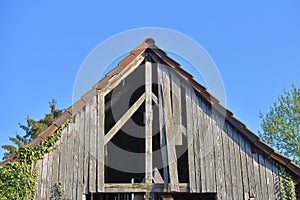 Old wooden and holey shed roof against a blue sky in a European village