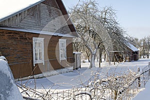 Old wooden house covered with fresh fallen snow. Uninhabited old winter cozy cottage in empty village. Rural wintertime