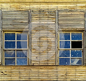 Old wooden house facade with two windows.