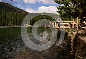 Old wooden house in the forest near the river and forest against the blue sky