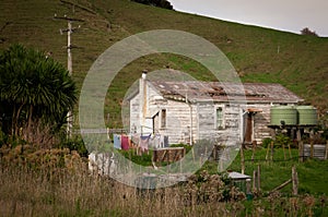 Old wooden house with peeling white paint near a roadside in rural Tolaga Bay, East Coast, North Island