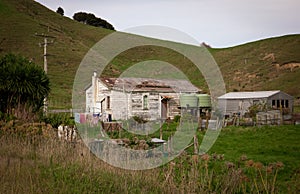 Old wooden house with peeling white paint near a roadside in rural Tolaga Bay, East Coast, North Island