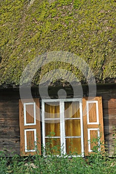 Old wooden house with wooden shutters and thatched roof. Rural buildings. Poland.