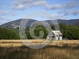 Old wooden hut at the edge of a forest beneath the mountains