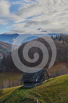 Old wooden hut in a landscape with mountains in the background in autumn