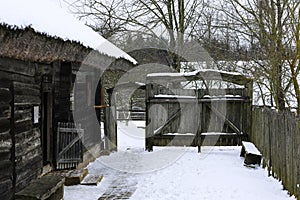 An old wooden hut, a log house with a thatched roof. Log house with barn. Courtyard with wooden fence and old gate.