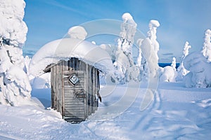 Old wooden hut in winter snowy forest in Finland, Lapland.