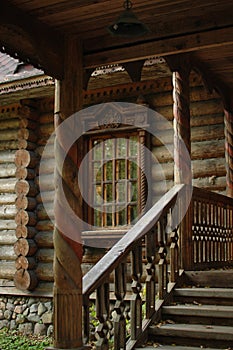 An old wooden hut. Wooden staircase, porch, window with platbands. Architecture.