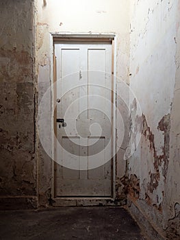 Old wooden interior door, locked, in dark corridor in abandoned old house.