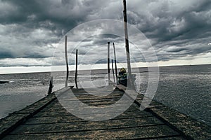 Old wooden jetty, pier, during storm on the sea.  sea horizon under huge dark storm sky and clouds