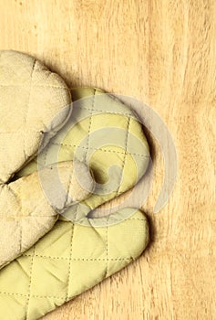 Old wooden kitchen board with protective oven glove