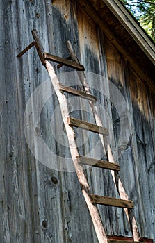 Old wooden ladder against a rustic wooden barn