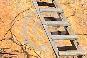 Old wooden ladder going up a red rock