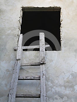 Old wooden ladder to window over the wall