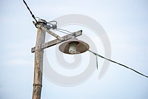Old wooden lamp post with light bulbs and wires. Installation of electrical cables on rural roads