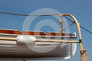 Old wooden lifeboat hoisted up on the side of an old tall ship, rigging details
