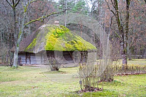 Old wooden log house. View with window, front door and with moss on the roof.