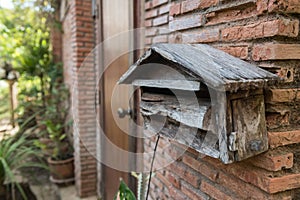 Old wooden mailbox by brick house front door