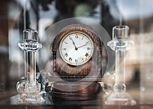 Old wooden mechanical wind up clock standing in antique shop window with reflections shining on glass time 11:11 eleventh minute