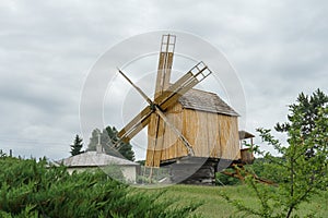Old wooden mill in a field; cloudy spring day