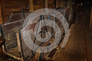 Old wooden mine train with rusty wheels in mine tunnel with wooden timbering