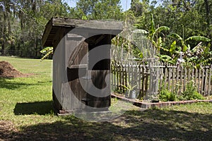 Old wooden outhouse by garden with forest in the background