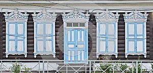 Old wooden painted white blue windows, door. Carved architraves, closed shutters. Ulan-Ude, Russia.