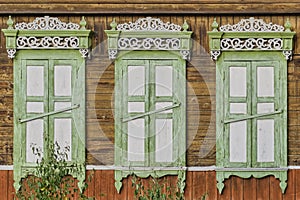 Old wooden painted white green windows, door. Carved architraves, closed shutters. Ulan-Ude, Russia.