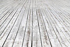 An old wooden pavement painted in white in a sunny day. Photo in perspective with selective focus