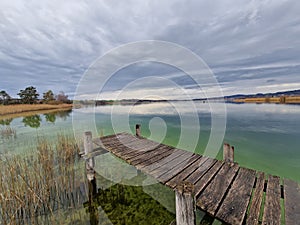 An old wooden pier on green Pfafikersee lake in autumn with cloudy sky just before rain