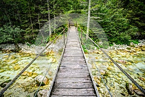 Old wooden plank bridge across beautiful river. Overcoming an obstacle concept.