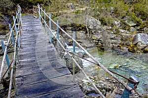 Old wooden plank bridge over mountain river photo