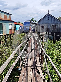 Old wooden plank bridge in rural landscape with tin and brass houses. Oriental rural landscapes. Asian architecture and